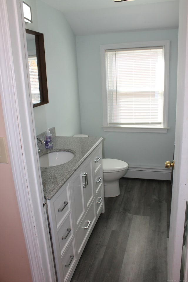 bathroom with hardwood / wood-style floors, vanity, toilet, and a baseboard radiator