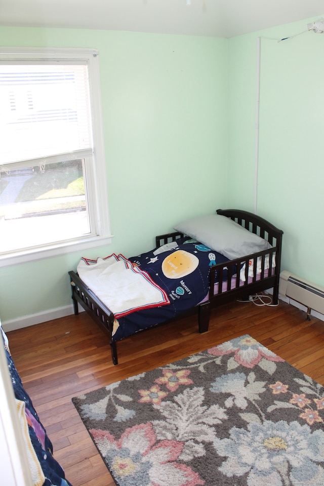 bedroom with wood-type flooring and a baseboard radiator