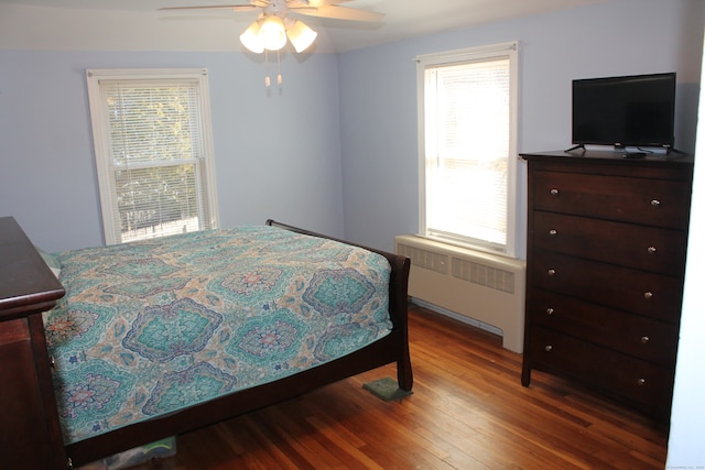 bedroom with multiple windows, wood-type flooring, radiator, and ceiling fan