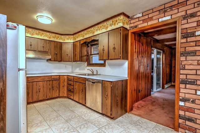 kitchen with light carpet, brick wall, wooden walls, sink, and dishwasher