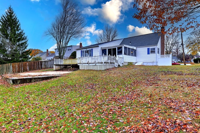 rear view of house with a wooden deck, a sunroom, and a yard