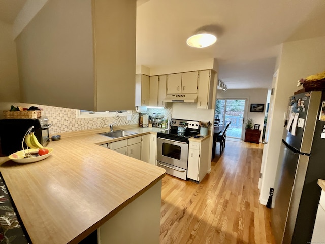 kitchen with kitchen peninsula, tasteful backsplash, stainless steel appliances, sink, and light hardwood / wood-style floors