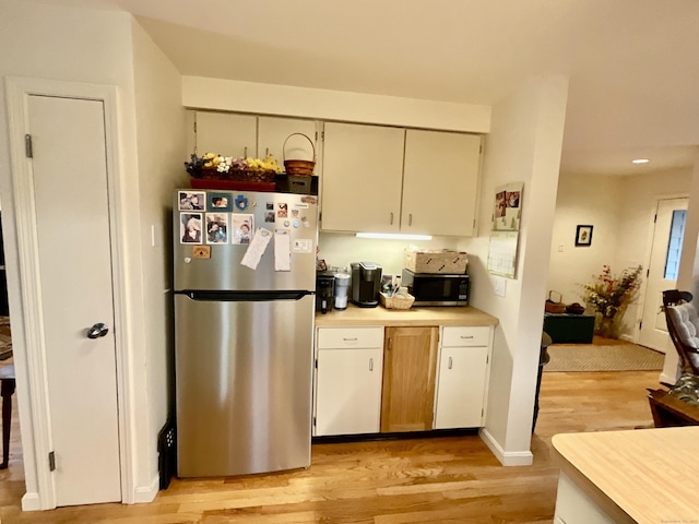 kitchen with appliances with stainless steel finishes, light hardwood / wood-style flooring, and cream cabinets