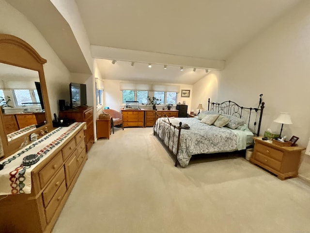 bedroom with lofted ceiling, light carpet, and track lighting