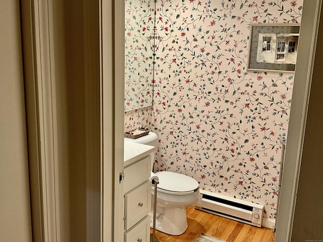 bathroom with wood-type flooring, vanity, toilet, and baseboard heating