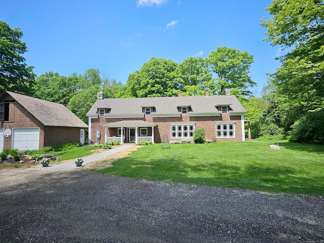 view of front of house featuring a front yard, covered porch, an outdoor structure, and a garage