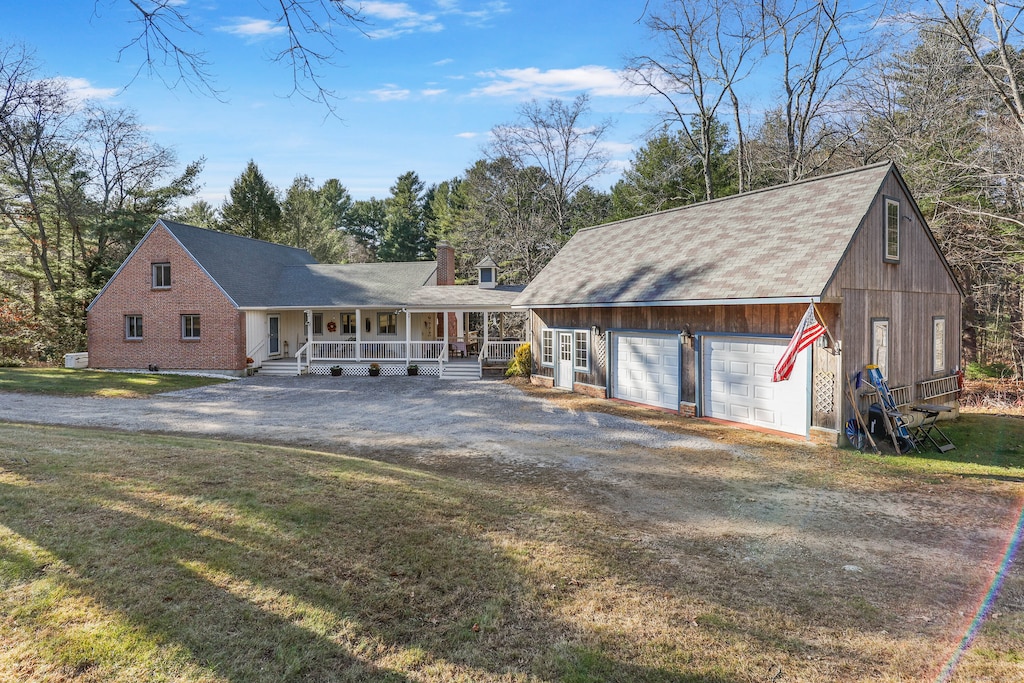 view of front of house featuring covered porch, a front yard, and a garage