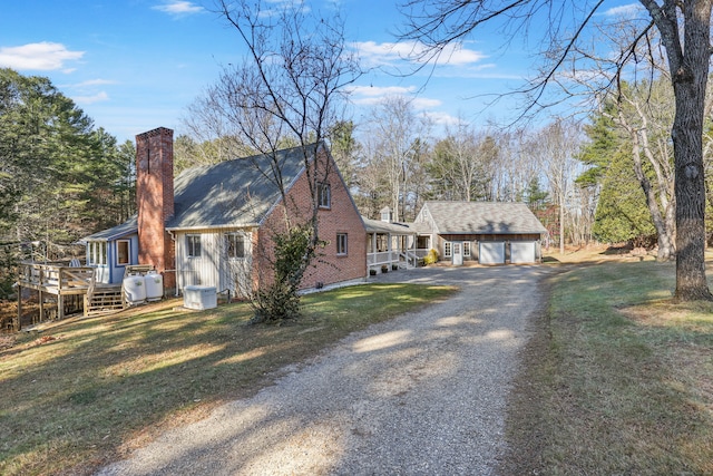 view of front of property featuring an outbuilding, a front lawn, a garage, and a deck