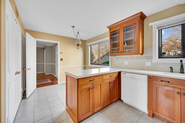 kitchen with pendant lighting, white dishwasher, sink, decorative backsplash, and kitchen peninsula