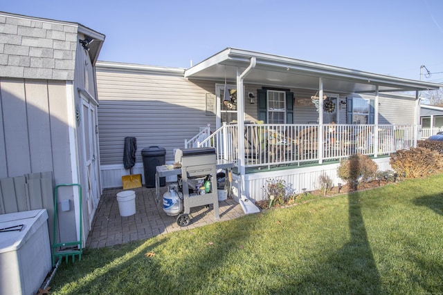 rear view of house featuring a lawn and a porch