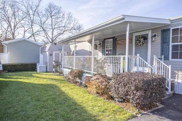 view of front facade featuring a storage unit, covered porch, and a front yard