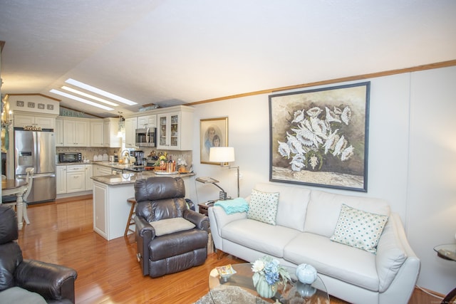 living room with lofted ceiling with skylight and light hardwood / wood-style flooring