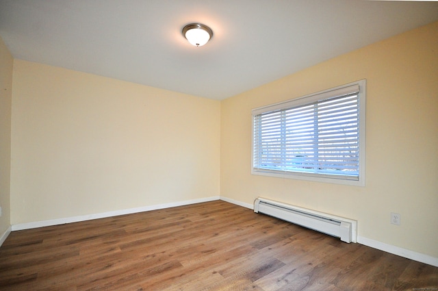 spare room featuring hardwood / wood-style floors and a baseboard heating unit