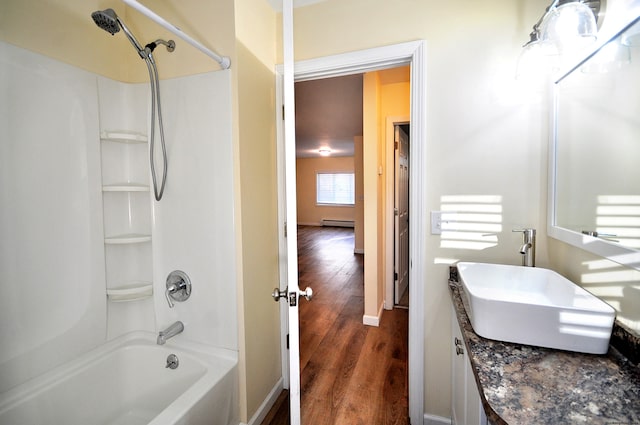 bathroom with vanity, wood-type flooring, tub / shower combination, and a baseboard heating unit