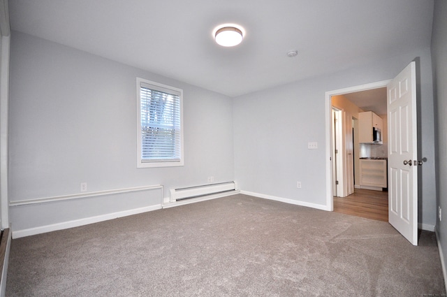 unfurnished room with carpet and a baseboard heating unit