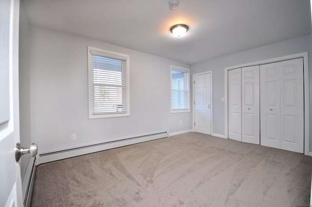 unfurnished bedroom featuring carpet flooring, two closets, and a baseboard heating unit