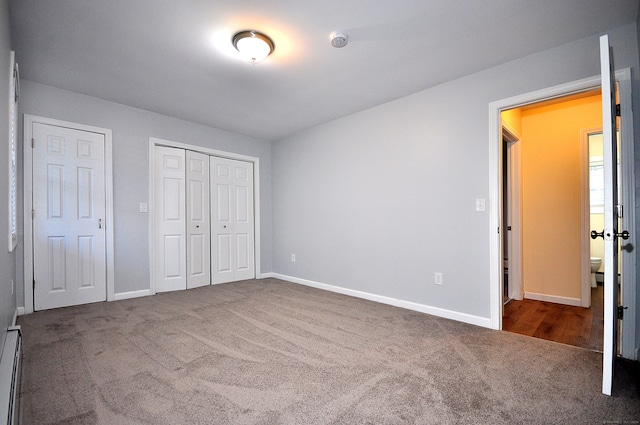 unfurnished bedroom featuring dark carpet and a baseboard heating unit