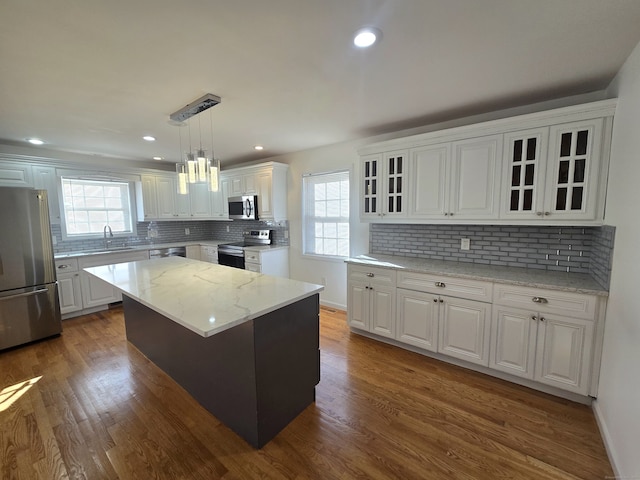 kitchen with a wealth of natural light, a center island, decorative light fixtures, and appliances with stainless steel finishes