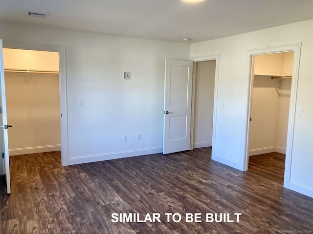 unfurnished bedroom with dark hardwood / wood-style flooring, a spacious closet, and a closet