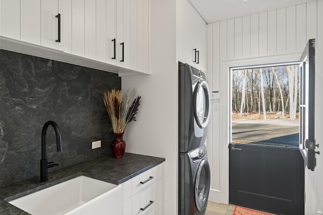 clothes washing area with sink, cabinets, and stacked washer / drying machine