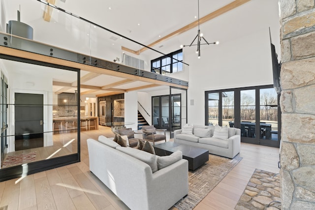 living room featuring a high ceiling, french doors, beamed ceiling, light hardwood / wood-style floors, and a chandelier