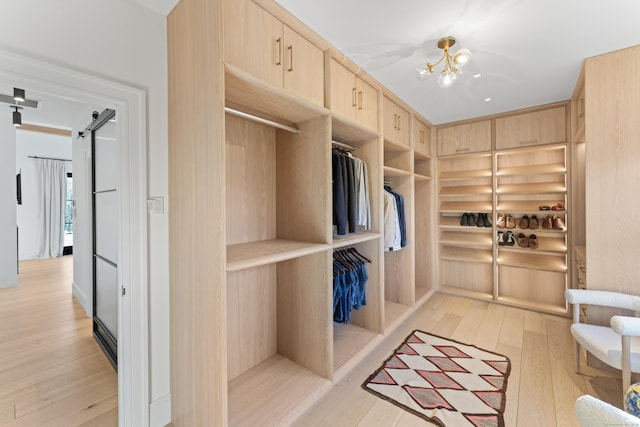 interior space with a chandelier, a barn door, and light hardwood / wood-style floors