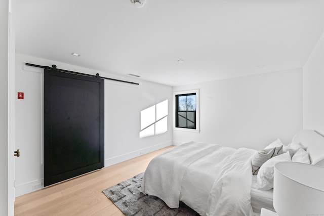 bedroom with light wood-type flooring and a barn door