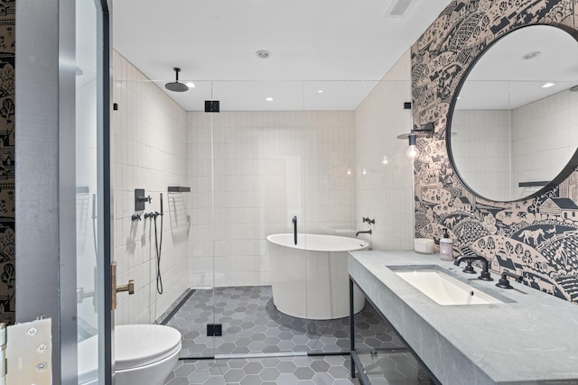 full bathroom with tile patterned floors, separate shower and tub, toilet, vanity, and tile walls