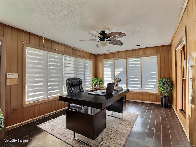 office area featuring a textured ceiling, ceiling fan, and wooden walls