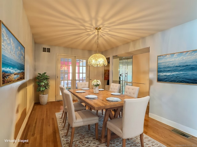 dining space with a chandelier, french doors, and light hardwood / wood-style flooring