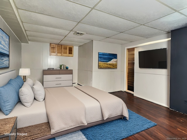 bedroom featuring a drop ceiling and dark wood-type flooring