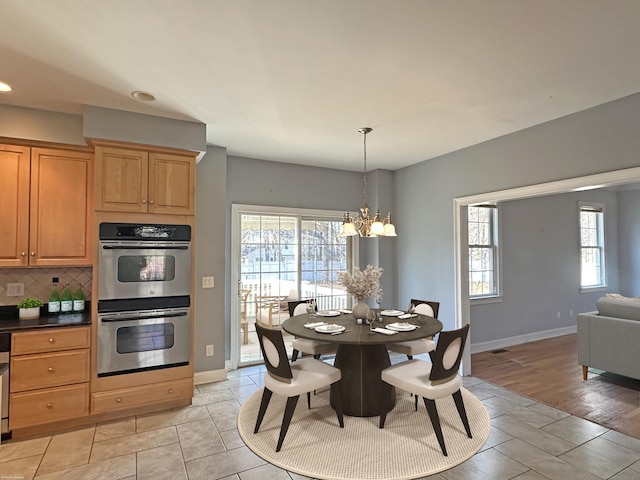 dining area featuring light wood-type flooring, plenty of natural light, and a notable chandelier