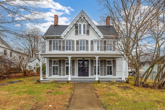 victorian-style house featuring covered porch and a front lawn