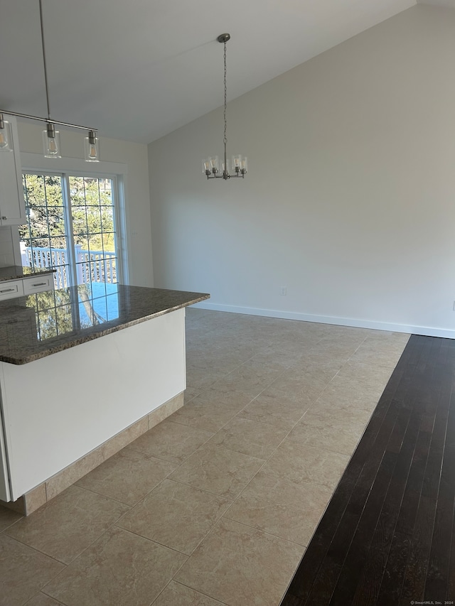 kitchen with white cabinetry, light hardwood / wood-style flooring, hanging light fixtures, and lofted ceiling