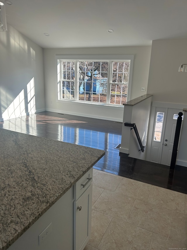 kitchen featuring white cabinetry, plenty of natural light, light hardwood / wood-style floors, and light stone counters