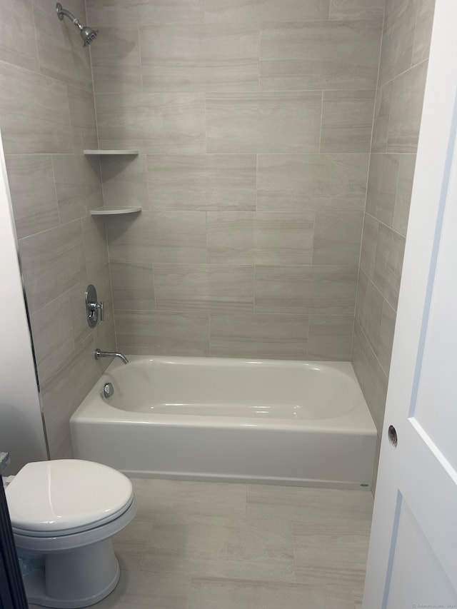 bathroom featuring tile patterned floors, tiled shower / bath combo, and toilet