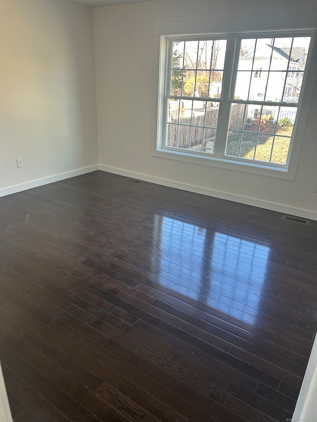 unfurnished room featuring dark hardwood / wood-style flooring and a healthy amount of sunlight