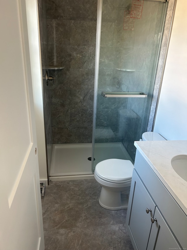 bathroom featuring vanity, toilet, and a shower with shower door