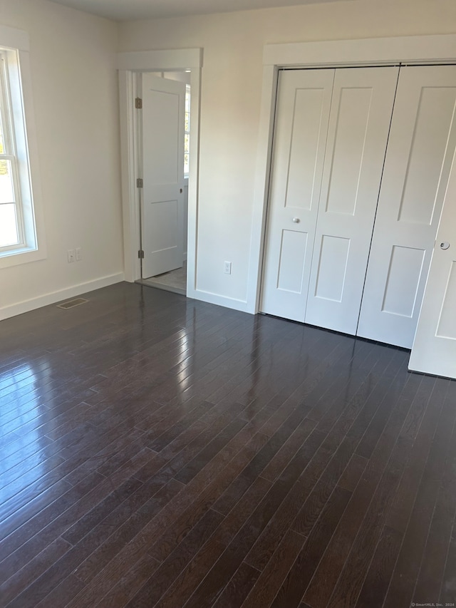 unfurnished bedroom with a closet and dark hardwood / wood-style flooring