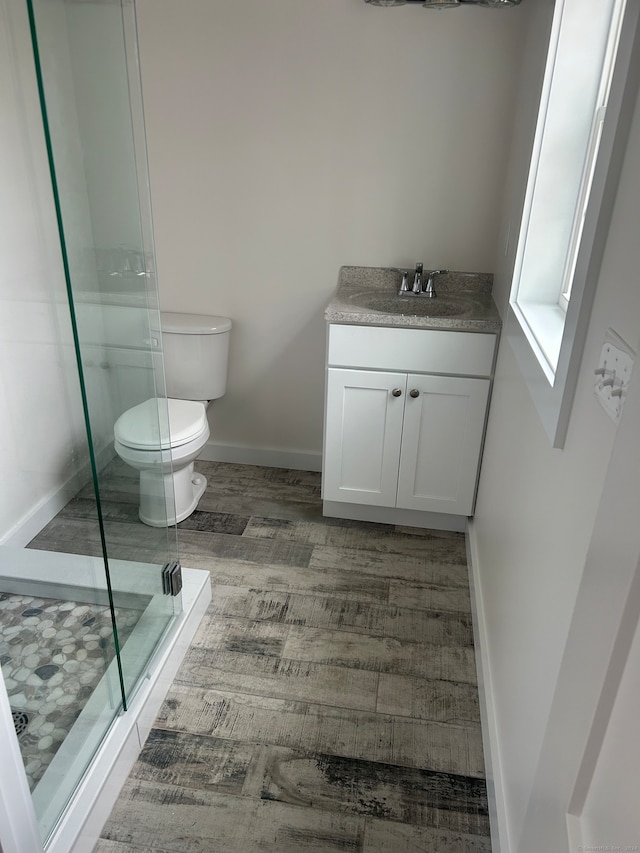 bathroom featuring hardwood / wood-style floors, vanity, toilet, and walk in shower