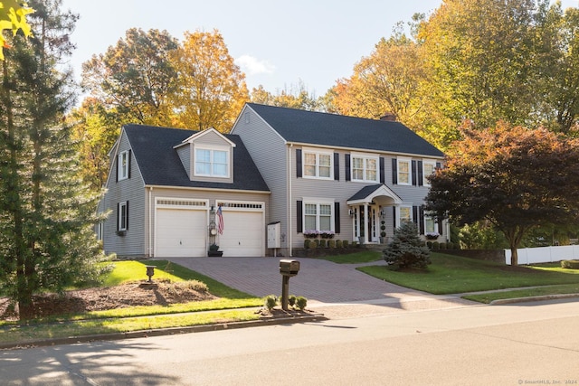 colonial home featuring a garage and a front lawn