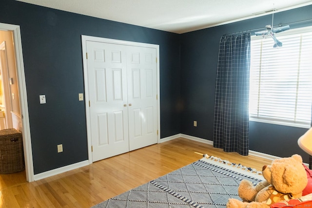 bedroom with multiple windows, a closet, and wood-type flooring