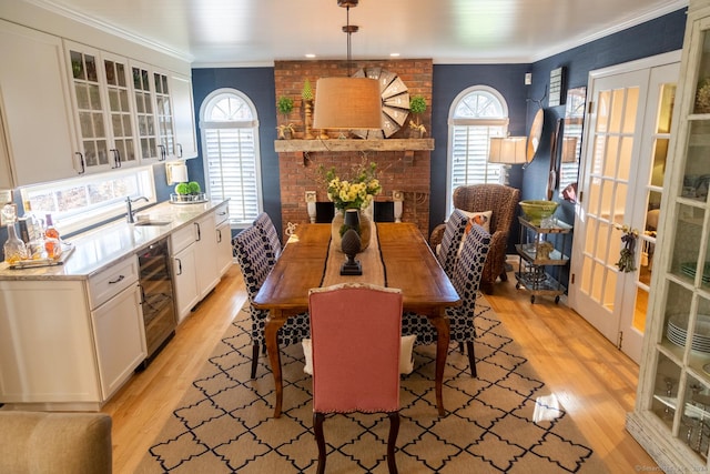 dining area featuring french doors, light wood-type flooring, wine cooler, and crown molding