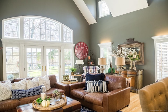 living room with a healthy amount of sunlight, french doors, a high ceiling, and light hardwood / wood-style flooring