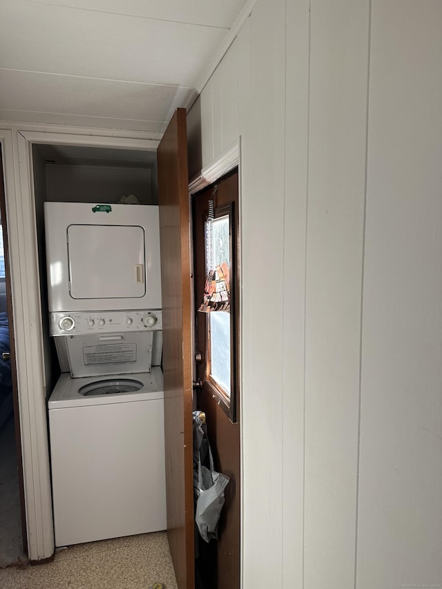 clothes washing area with stacked washer / drying machine and wooden walls