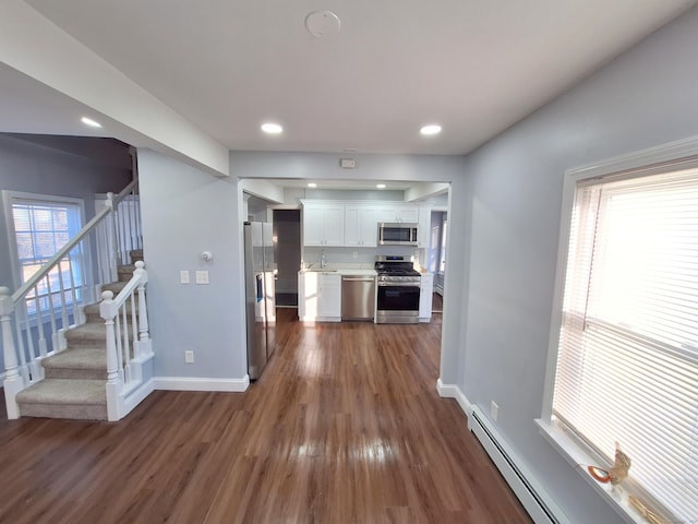 kitchen featuring white cabinetry, a healthy amount of sunlight, a baseboard heating unit, and appliances with stainless steel finishes