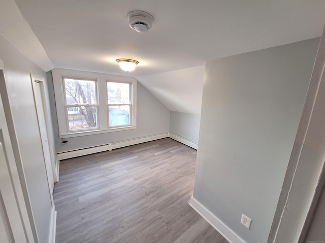 additional living space with a baseboard heating unit, light wood-type flooring, and lofted ceiling