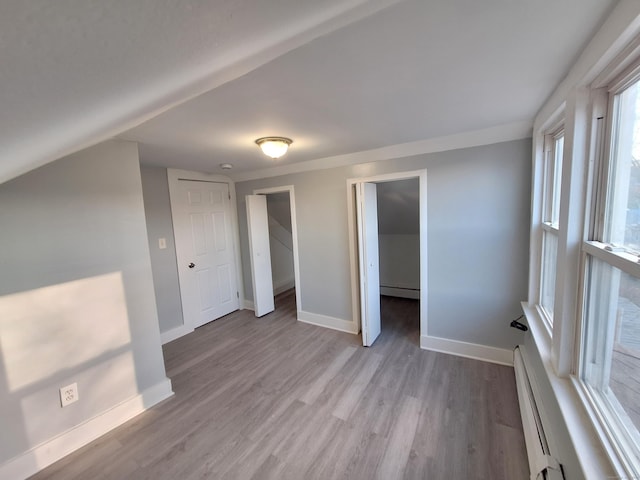 unfurnished bedroom featuring light hardwood / wood-style floors, baseboard heating, and a closet