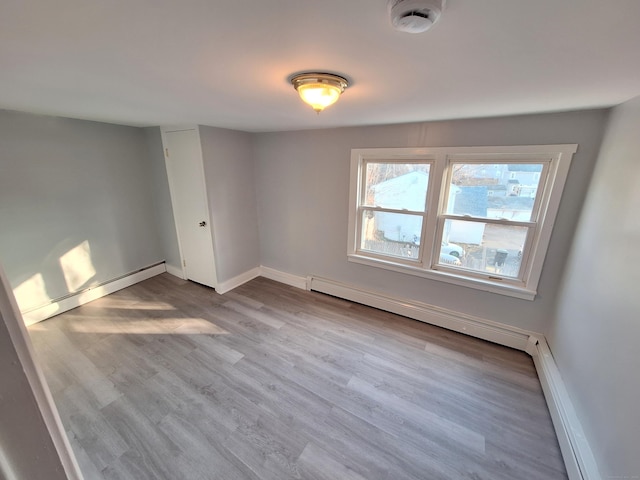 spare room with baseboard heating and light wood-type flooring