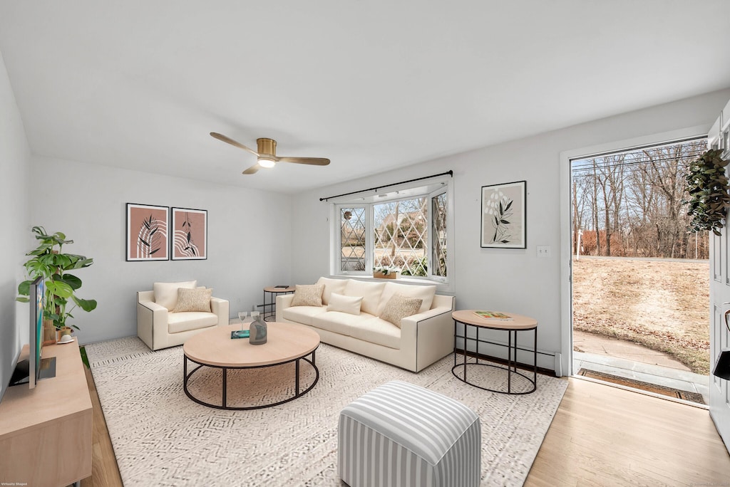 living room featuring baseboard heating, light hardwood / wood-style floors, plenty of natural light, and ceiling fan